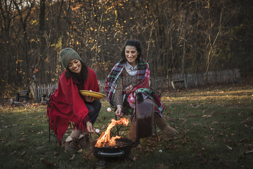 两个女人在营火上烤棉花糖图片