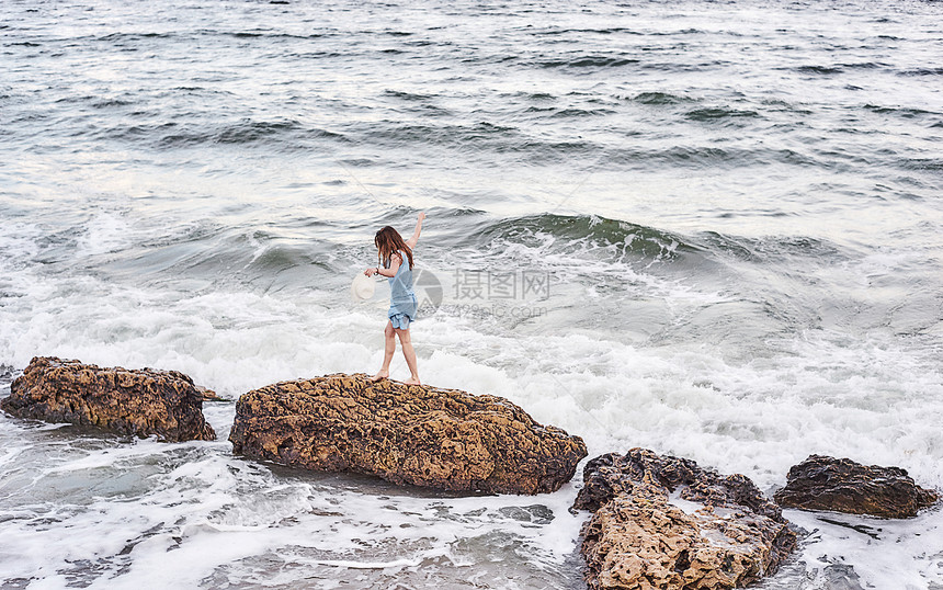 女人走在海边礁石上图片