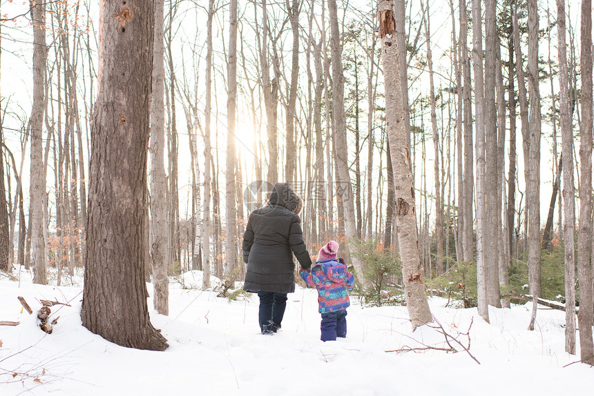母亲和女儿在雪中行走图片