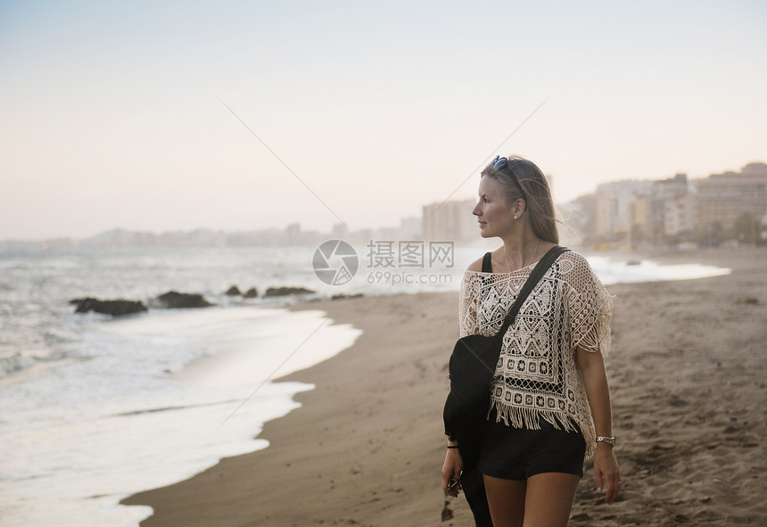 西班牙海滩上行走的妇女图片