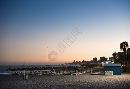 西班牙日落时海滩上的阳伞图片
