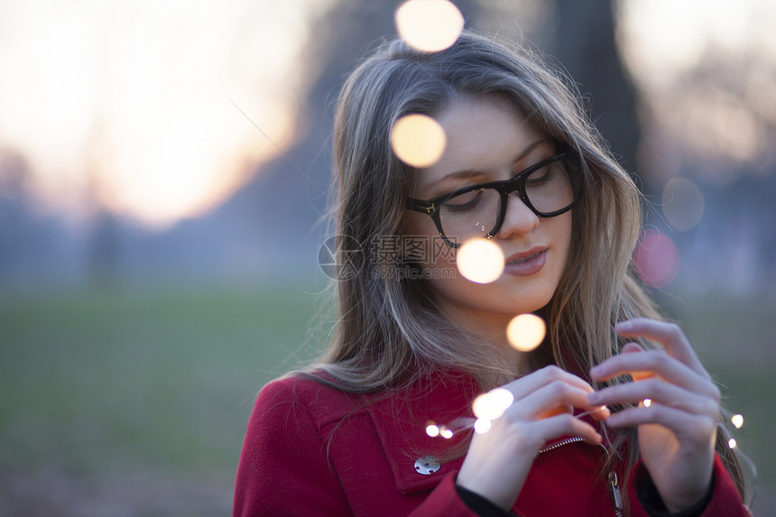 公园中的年轻女子看着她手中的灯光联合王国伦敦图片