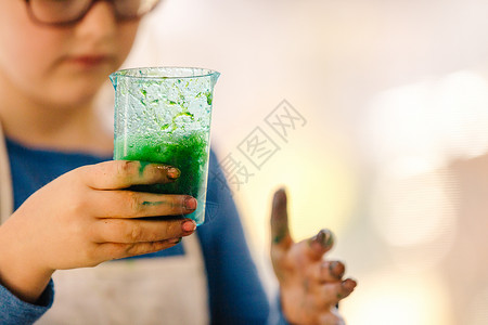 女孩做科学实验时拿着装有绿色液体的量杯图片
