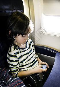 飞机上在mp3播放器中选择音乐的男孩图片