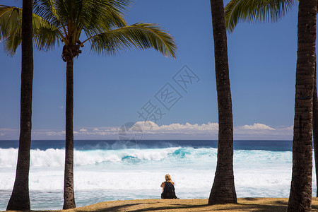 坐在海滩上看海的女游客图片