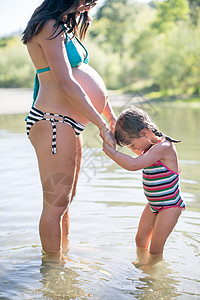 怀孕母亲和女儿站在湖中握着手图片