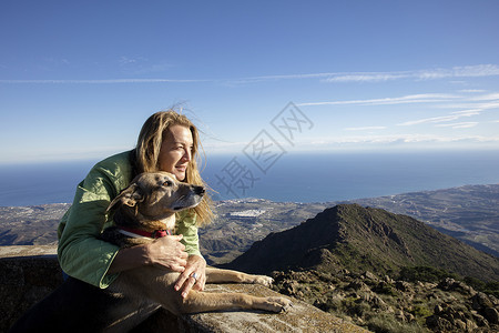 山顶上的女性抱着狗看风景图片