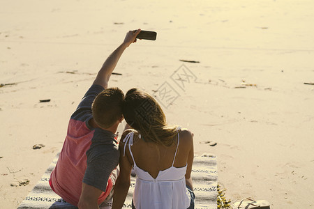 坐在海滩边自拍的一对情侣图片