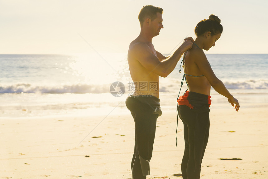 海滩帮女朋友穿泳衣的男士图片