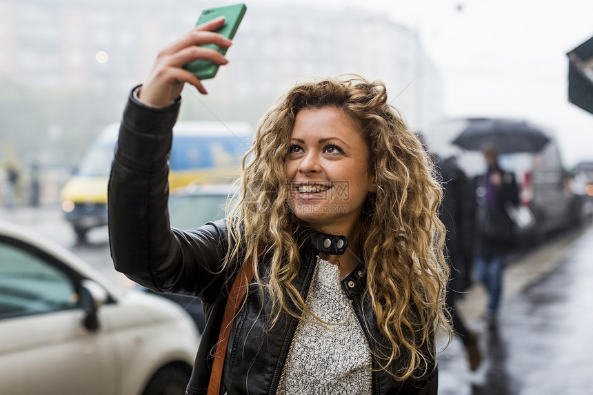 街上拿着手机自拍的女人图片