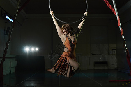年轻女杂技演员悬吊在杂技铁环上图片