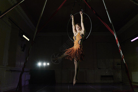 年轻女杂技演员悬吊在杂技铁环上图片
