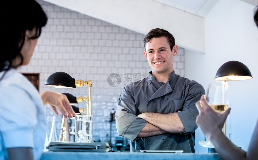 男士站在酒吧后面两个顾客坐在酒吧喝着饮料图片