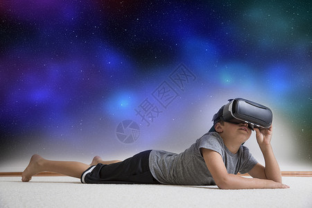 男孩趴在地板上戴着虚拟现实头盔看着数字合成的夜空图片