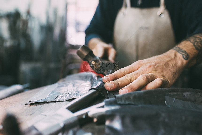 金属工人在铸造车间中锤制铅金属的手图片