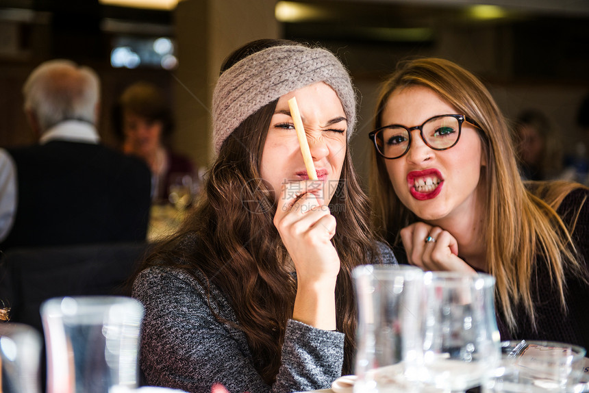 两名年轻妇女在咖啡馆对着镜头做鬼脸图片