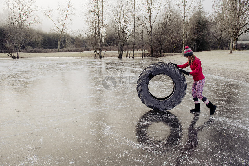 冷冻湖上的妇女滚动轮胎图片