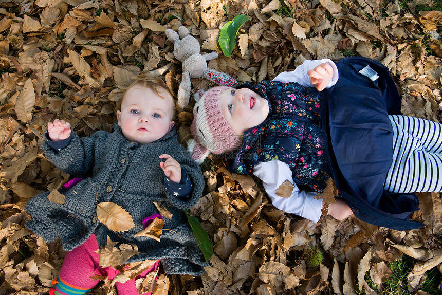 女幼儿和婴头部肖像躺在公园秋叶图片
