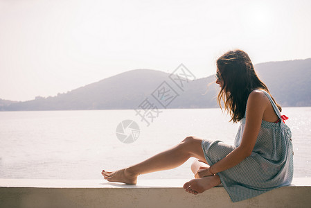 海上坐在墙的年轻妇女图片