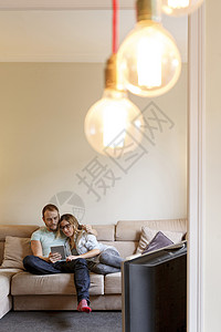 成年夫妇在沙发上看平板电脑放松图片