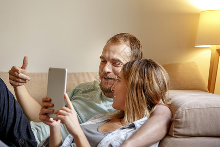 成年夫妇在沙发上看平板电脑放松图片