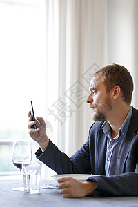 坐在晚餐桌上的男人看着手机图片
