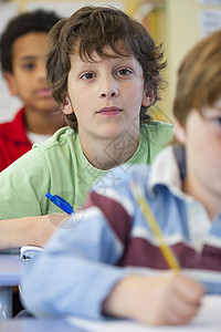小学男生在课堂上记笔记背景图片