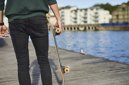 年轻人在河边拿着滑板行走布里斯托尔图片