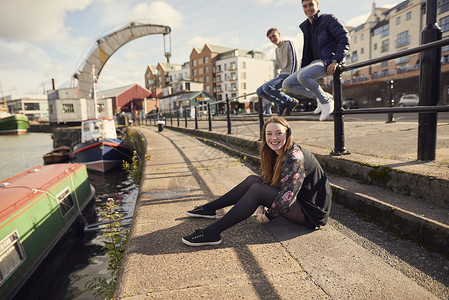 三个朋友坐在河边看着镜头微笑英国布里斯托尔图片
