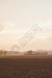 一片雾中田地和遥远的农场建筑图片