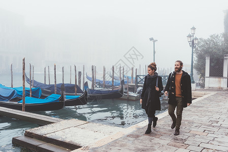 沿意大利威尼斯明水河滨漫步的一对夫妇图片