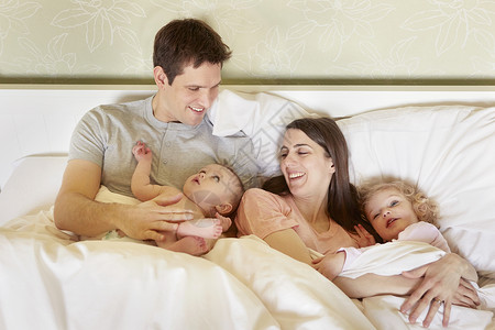 夫妻抱着孩子在床上图片