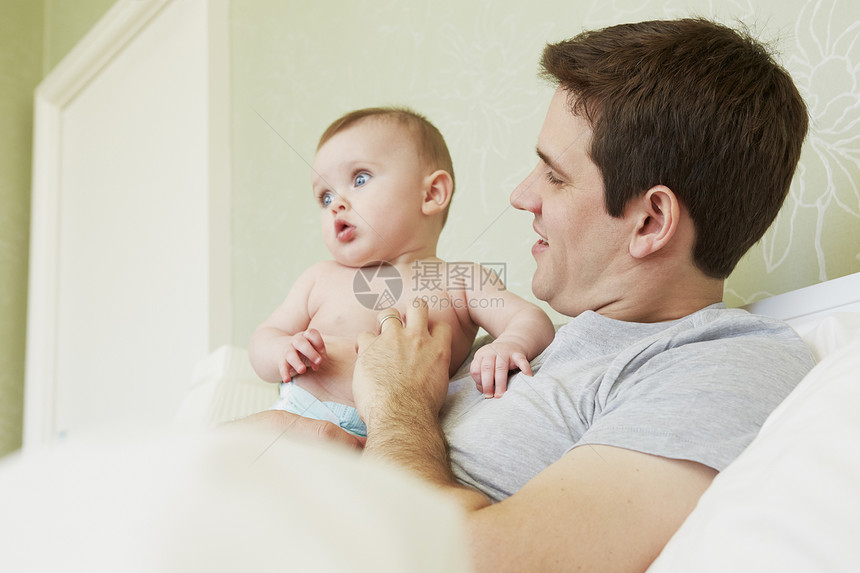 男子抱着女婴在床上图片