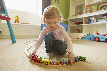 真人小孩在游戏室地板上玩火车的女幼儿背景
