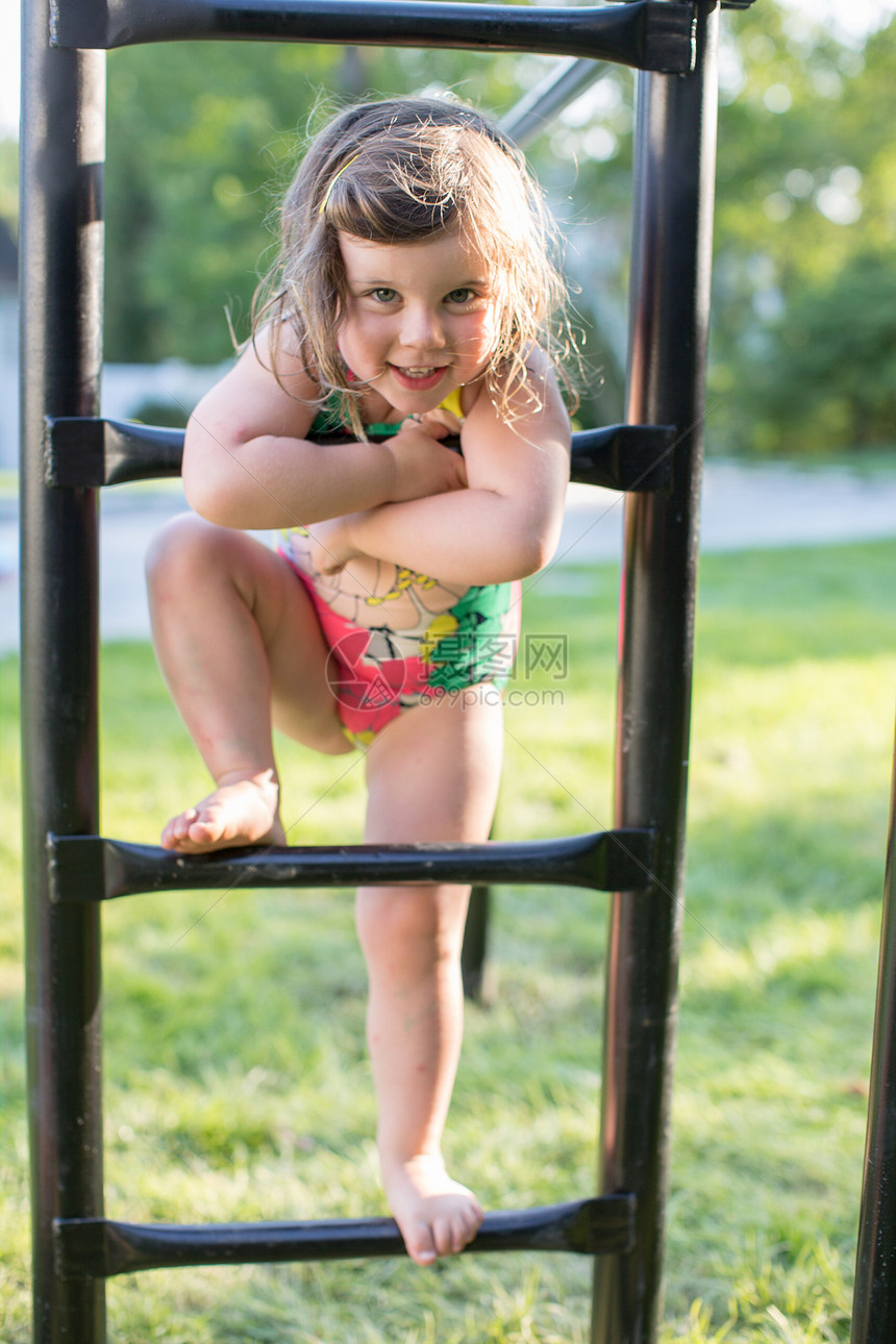 穿着泳装的女孩肖像站在花园攀爬架上图片