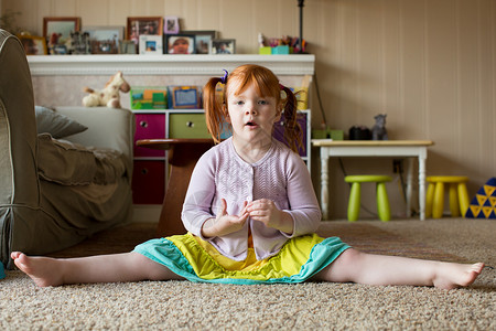 红头发坐在地毯上腿伸展的年轻女孩肖像图片