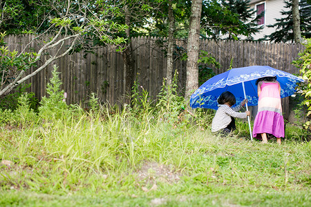 把海滩伞架在花园里的孩子图片
