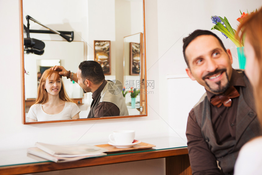 男美发师在店里给女顾客查看发型图片