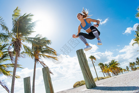 年轻女培训在海滩空中跳跃图片