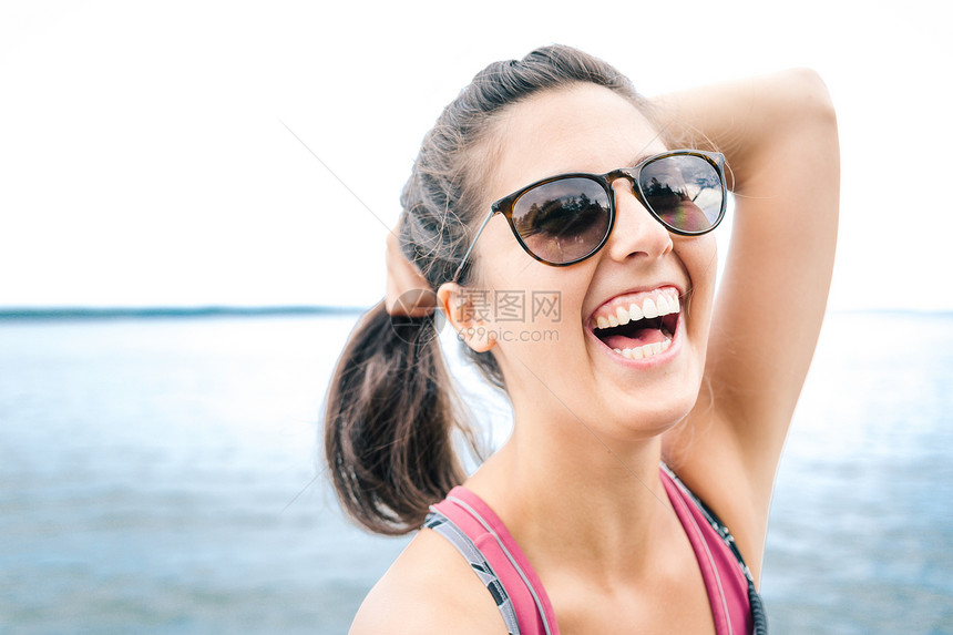 美国缅因州戴着墨镜的年轻女子在海边欢笑图片
