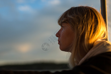 美国缅因州海岸日落时一名女子从船上向外眺望图片