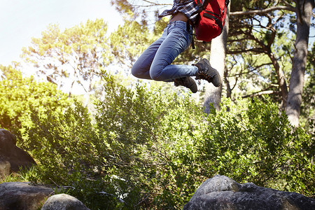年轻妇女穿着背包在空气中跳跃低层图片