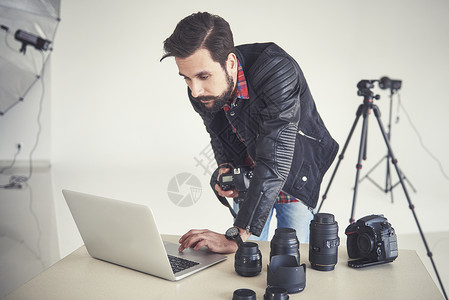 男摄影师在笔记本电脑上观看摄影棚照片拍图片
