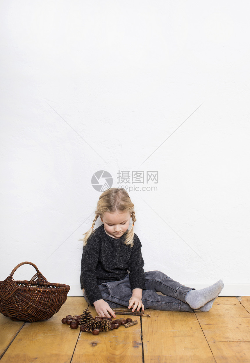 女孩坐在地板上整理松果和汁图片