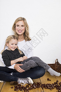 母亲和女儿的肖像坐在地板上周围着糖果和松图片