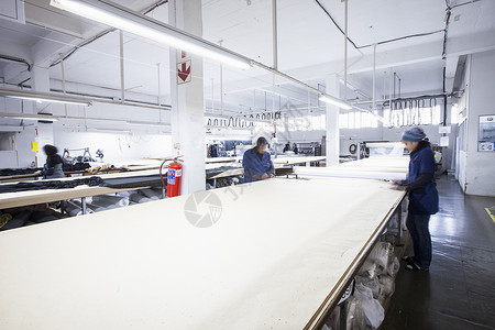 服装厂中在纺织上作标记的男女工厂人纺织品高清图片素材