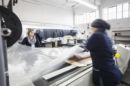 工厂女在服装厂中将纺织脱到裁制机中年妇女高清图片素材