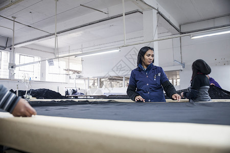 服装厂在工作桌上拆纺织品的工厂人图片