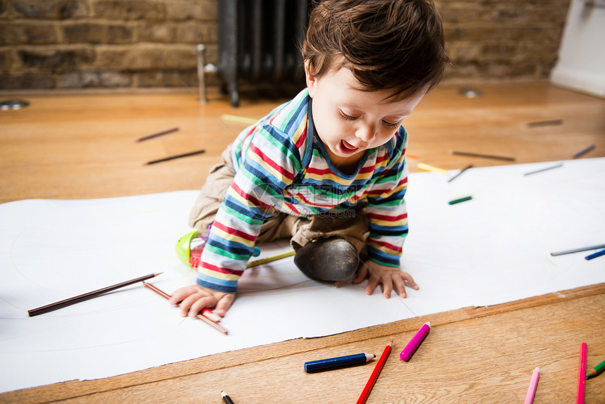 男幼儿坐在地板上用长纸画图片
