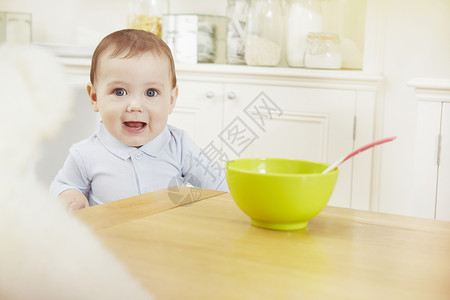 把早餐碗放在桌上的婴儿男孩肖像图片